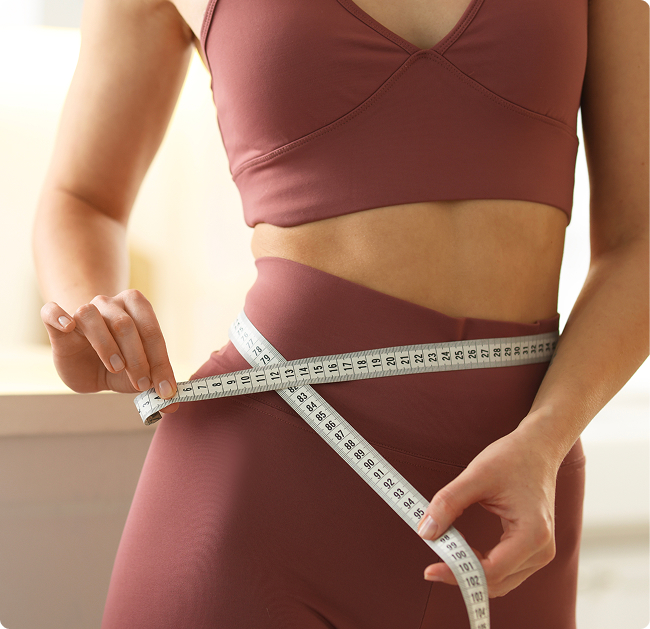 Woman measuring her waist with a tape measure