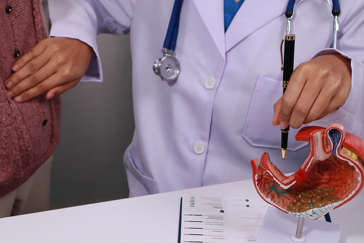 A doctor referring to a model while attending to a patient experiencing GERD symptoms