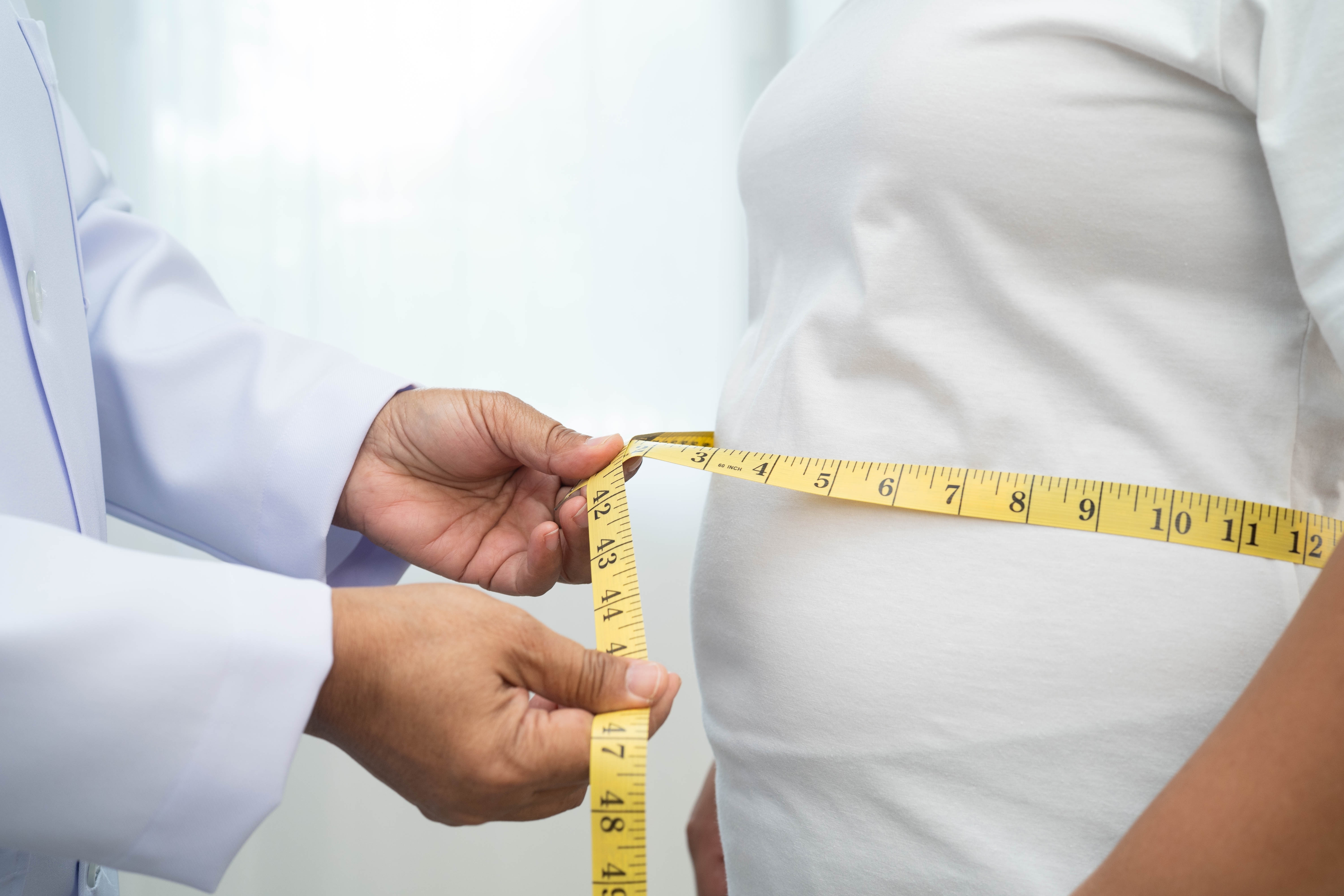 Doctor wrapping measuring tape around an obese woman