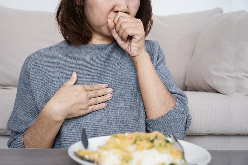 Woman experiencing acid reflux symptoms while eating a meal