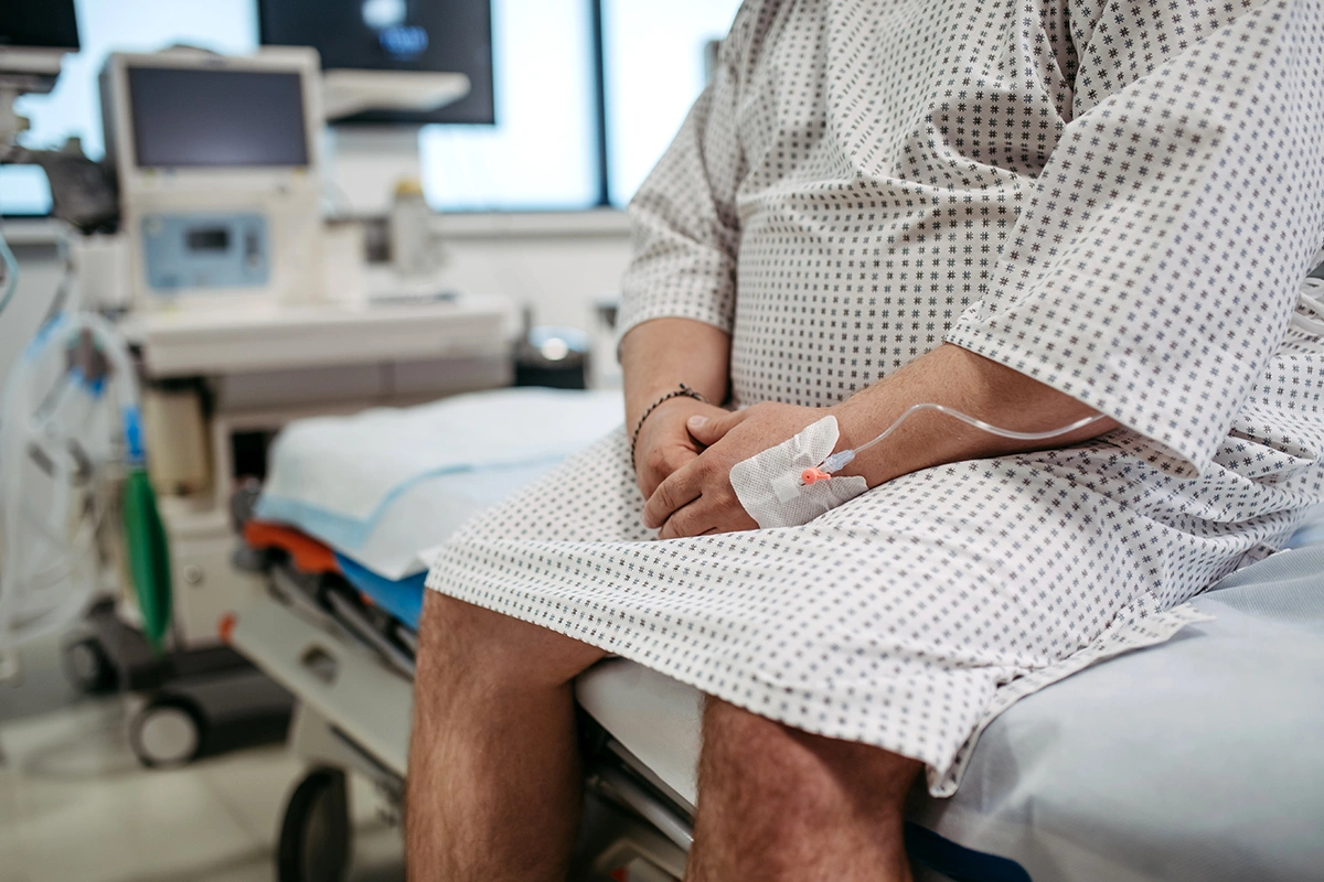 A man seated on a hospital bed while waiting for bariatric sleeve surgery