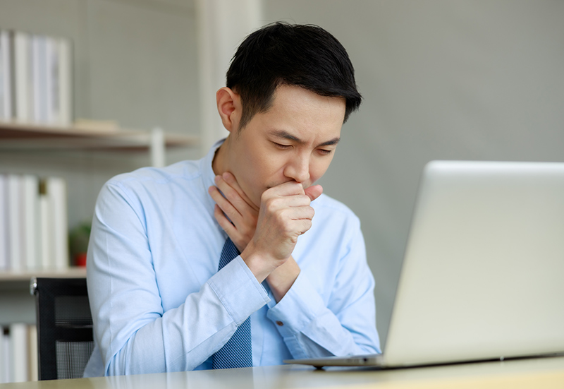 Man holding his throat while experiencing throat discomfort associated with silent reflux symptoms