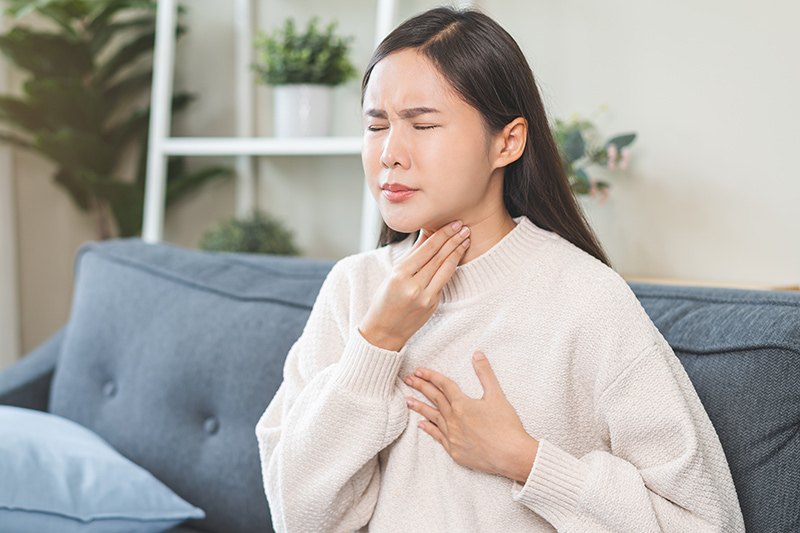 Woman experiencing silent reflux symptoms with persistent throat irritation