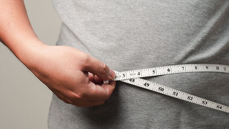 Man standing with a measuring tape wrapped around his waist